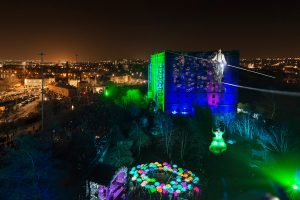 Cirque Bijou - Wire walker on a 40m high wire with the Bristol cityscape beneath him and a circle of colourful LED Umbrellas