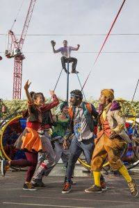 Cirque Bijou - Source, a group of dancers wearing colourful costumes celebrate during the finale of an outdoor street show