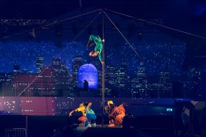 Cirque Bijou - Circus artists perform on and around a chinese pole with an amazing video mapped city scape backdrop