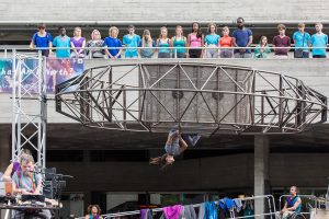 Extraordinary Bodis performer Aislinn Mulligan swings from structure in What Am I Worth? National Theatre River Stage. Image Rob Harris