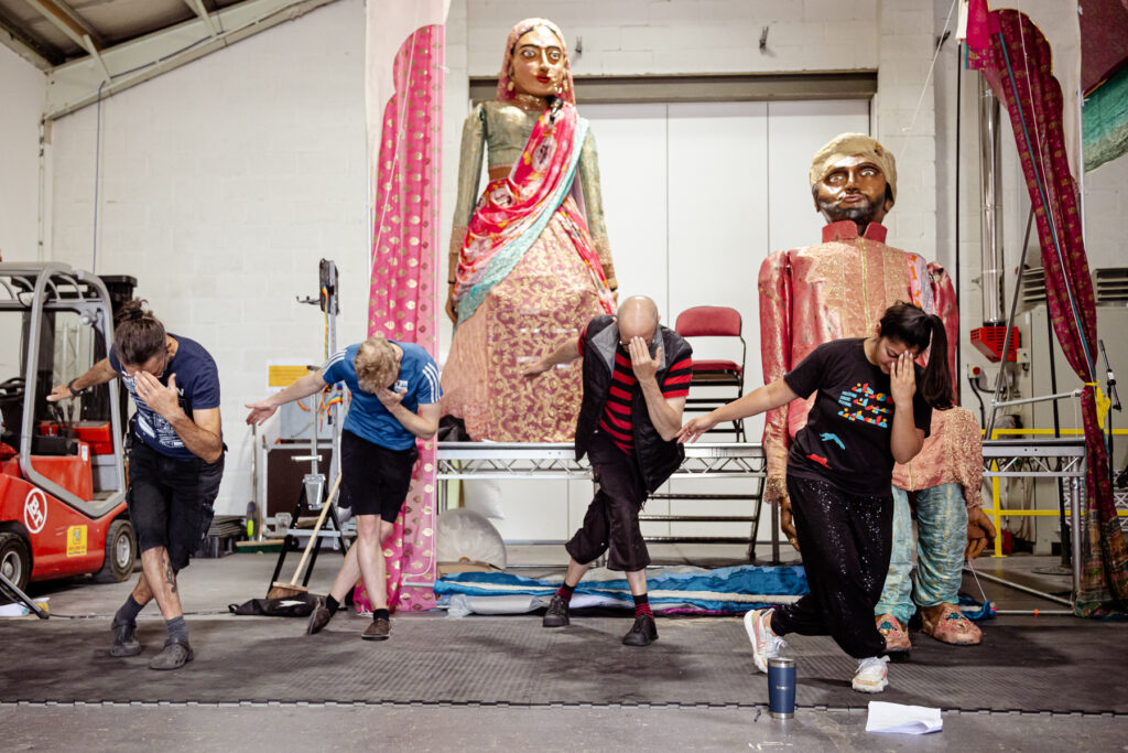 Dancers perform in front of two large puppets