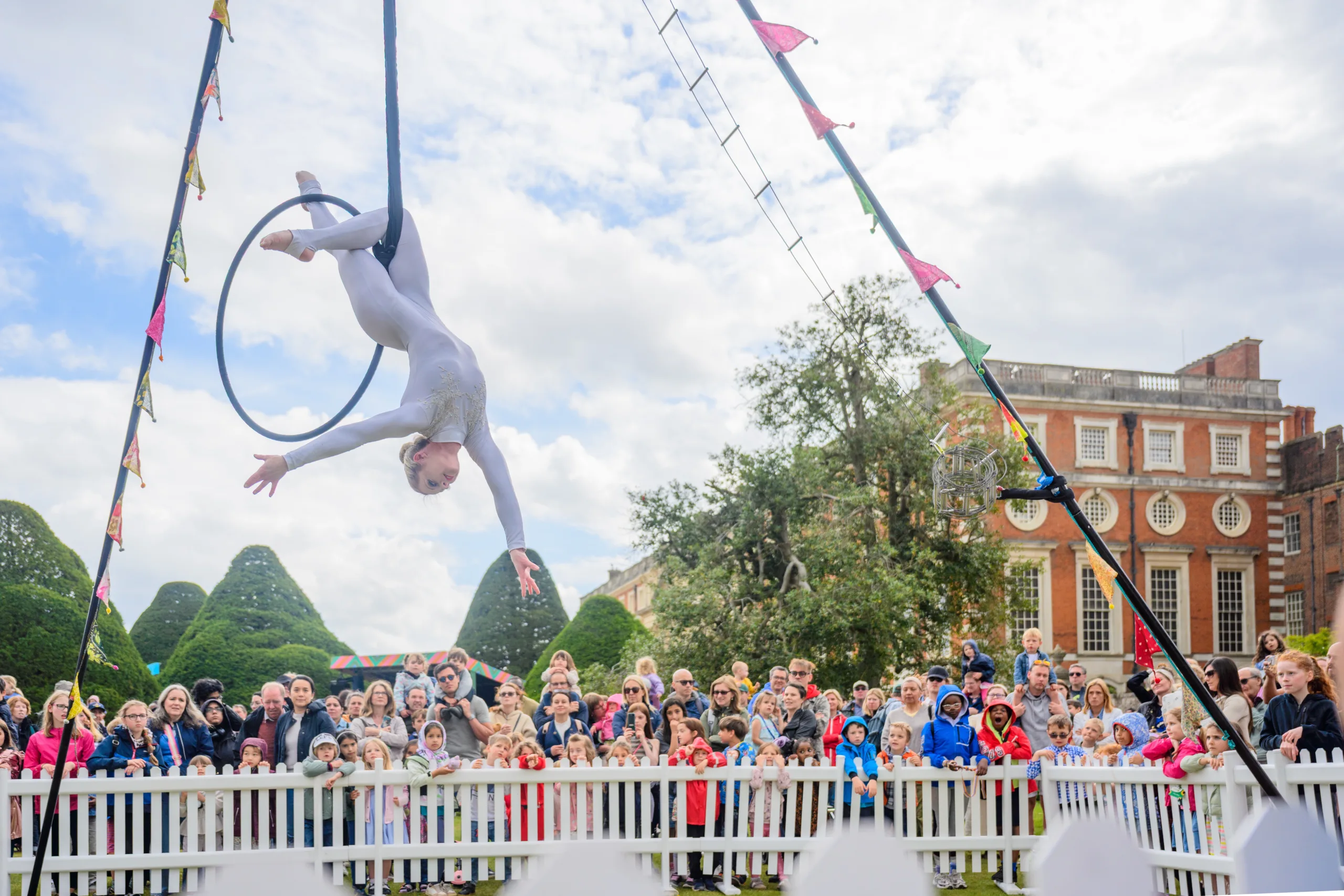Aerialist Nicki Pearson upside down on an aerial hoop with a crowd watching