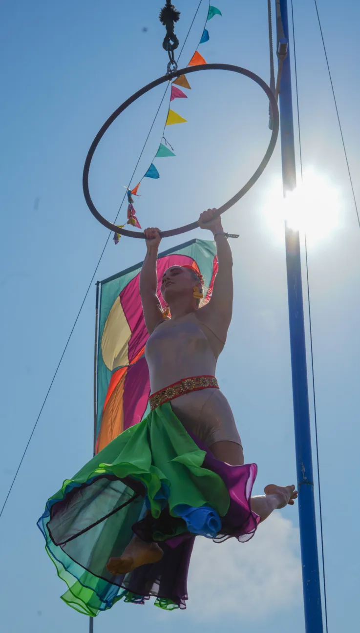 Aerialist at Camp Bestival holding onto a hanging hoop