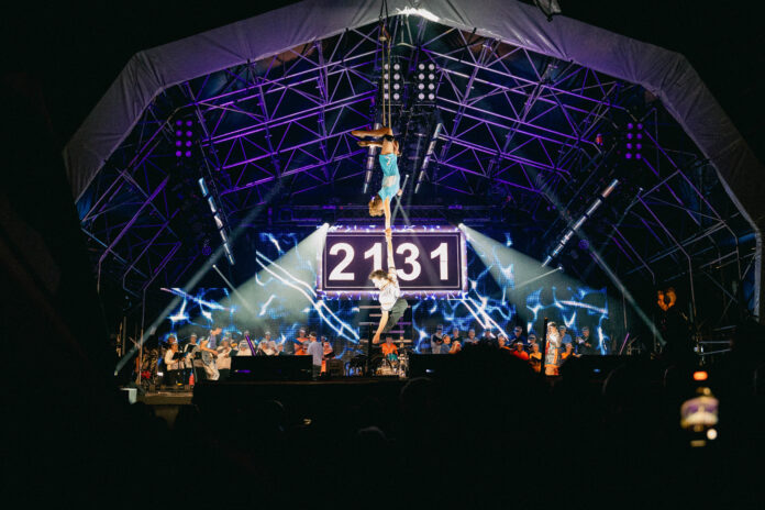 Wide shot of the main stage during finale performance with aerialists Tilly and Jonny suspended above the stage