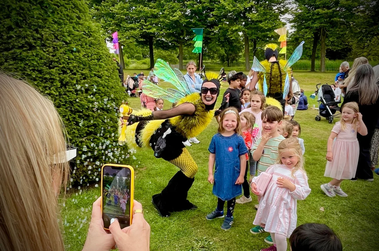 Children having their picture taken with walkabout performers dressed as bumble bees