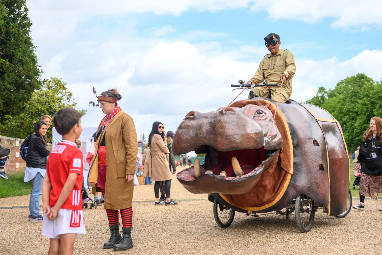 Explorer riding a giant mechanical hippo through the crowd at Hampton Court