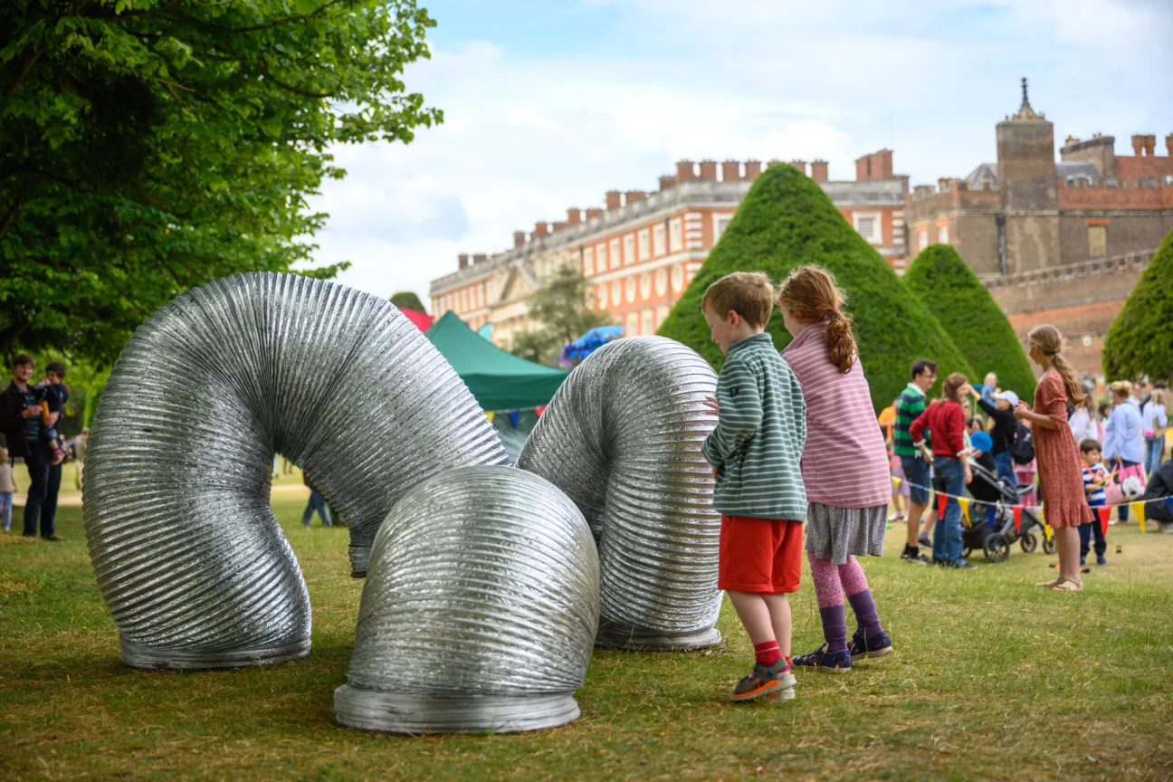 Children interacting with performers inside giant silver slinkies