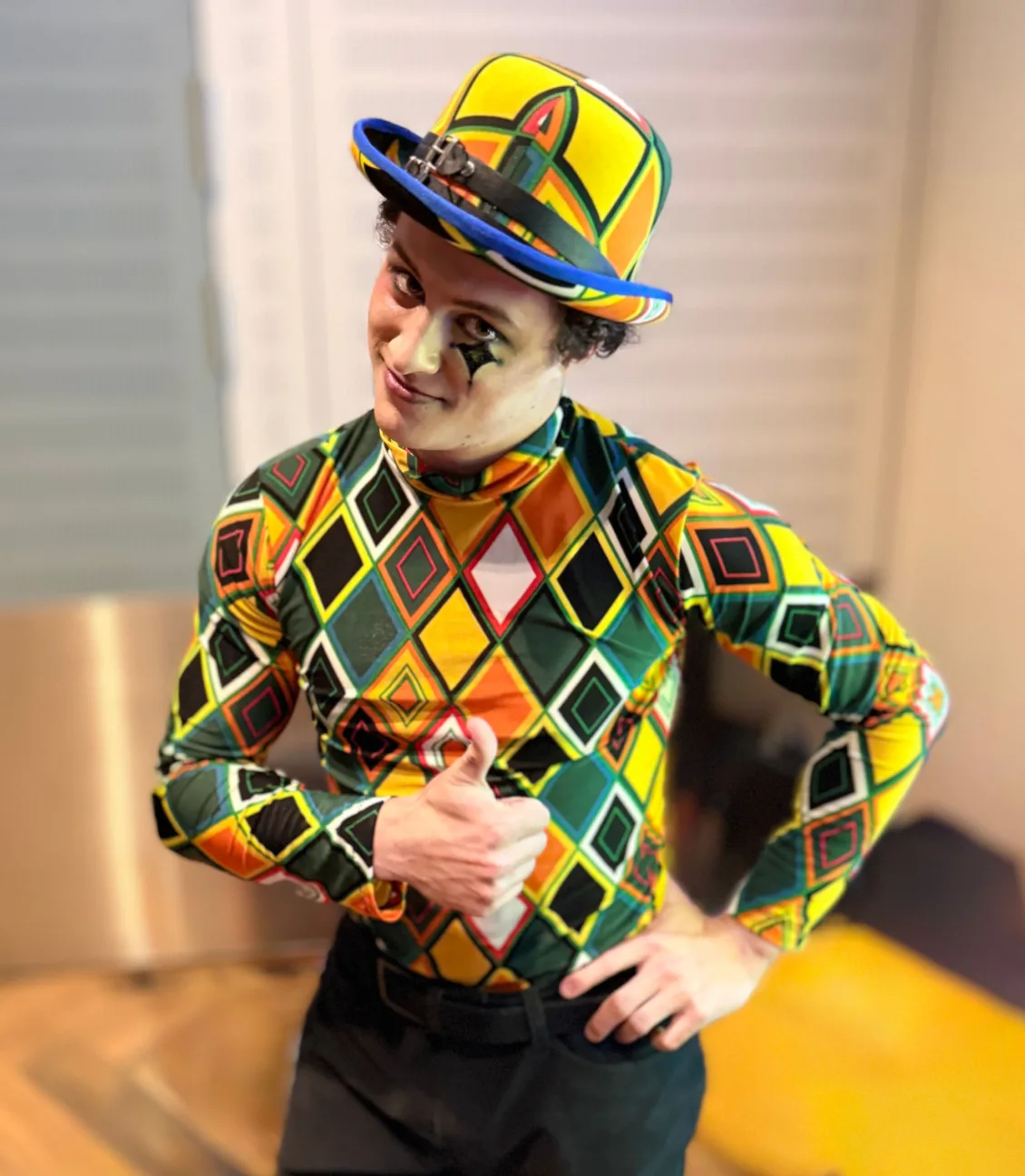 Circus performer in harlequin costume giving the thumbs up to the camera