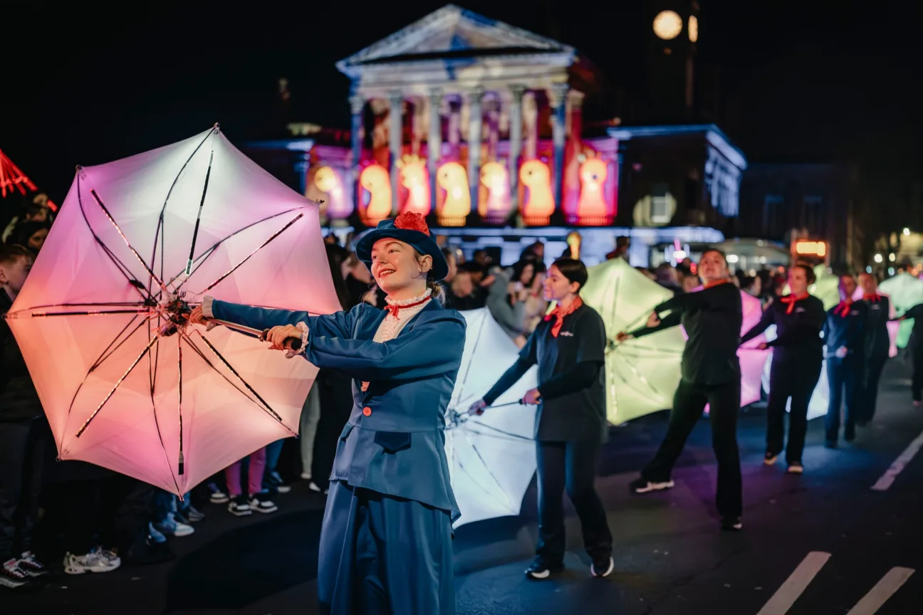 Marry Poppins character holding one of our light up umbrellas leading dancers through the parade