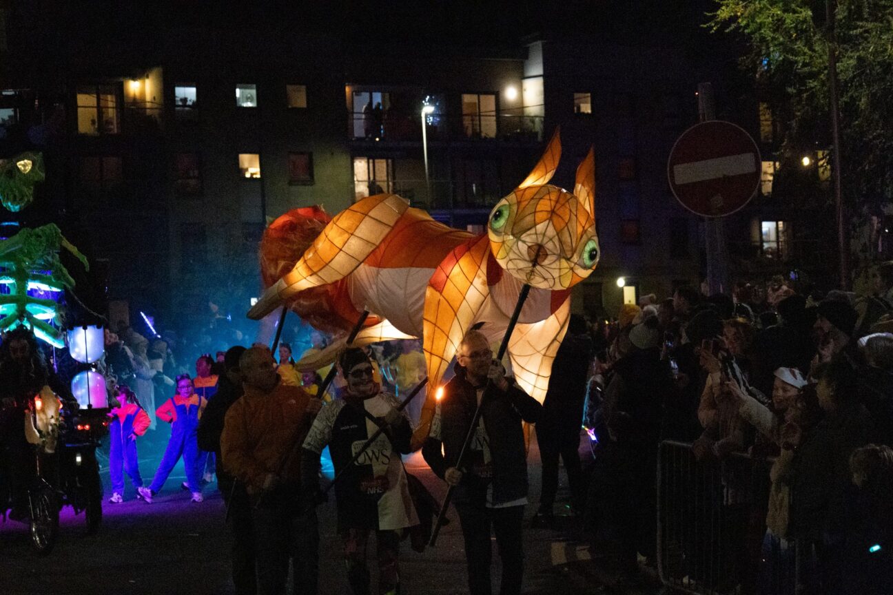 four people holding up squirrel puppet in the parade