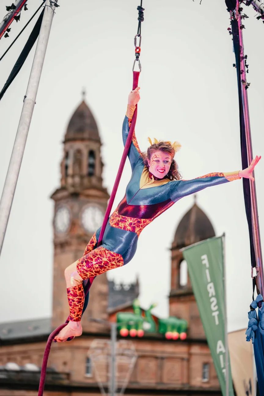 Aerial performer on a rope waving to the crowd
