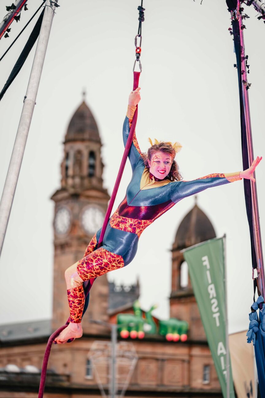 Aerial performer on a rope waving to the crowd