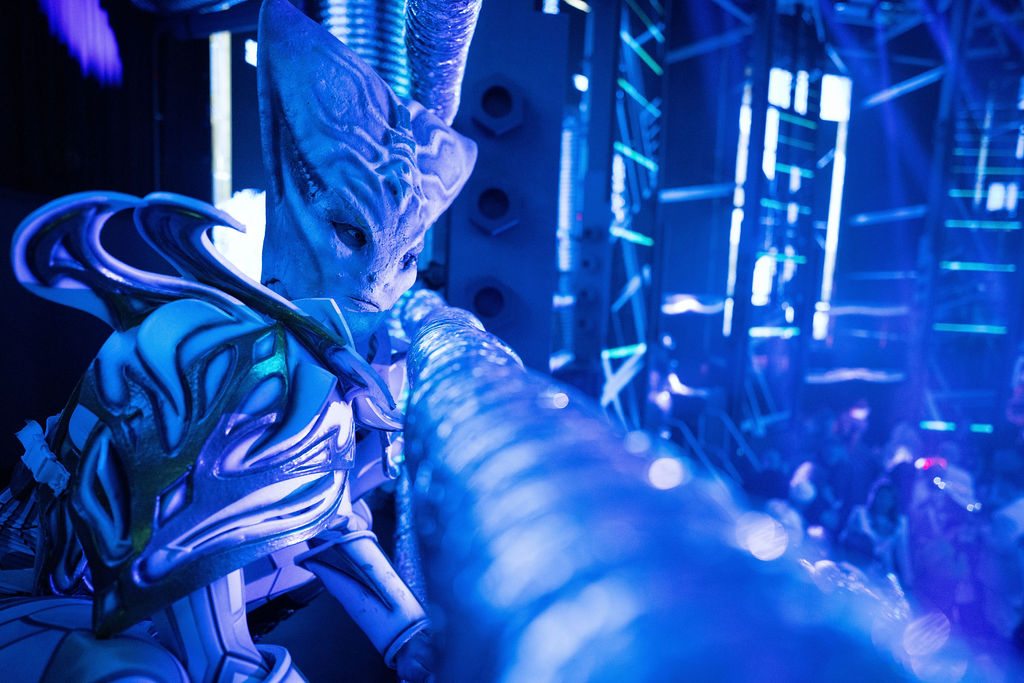 Dancers dressed as aliens stand ready to enter the dancefloor for their performance