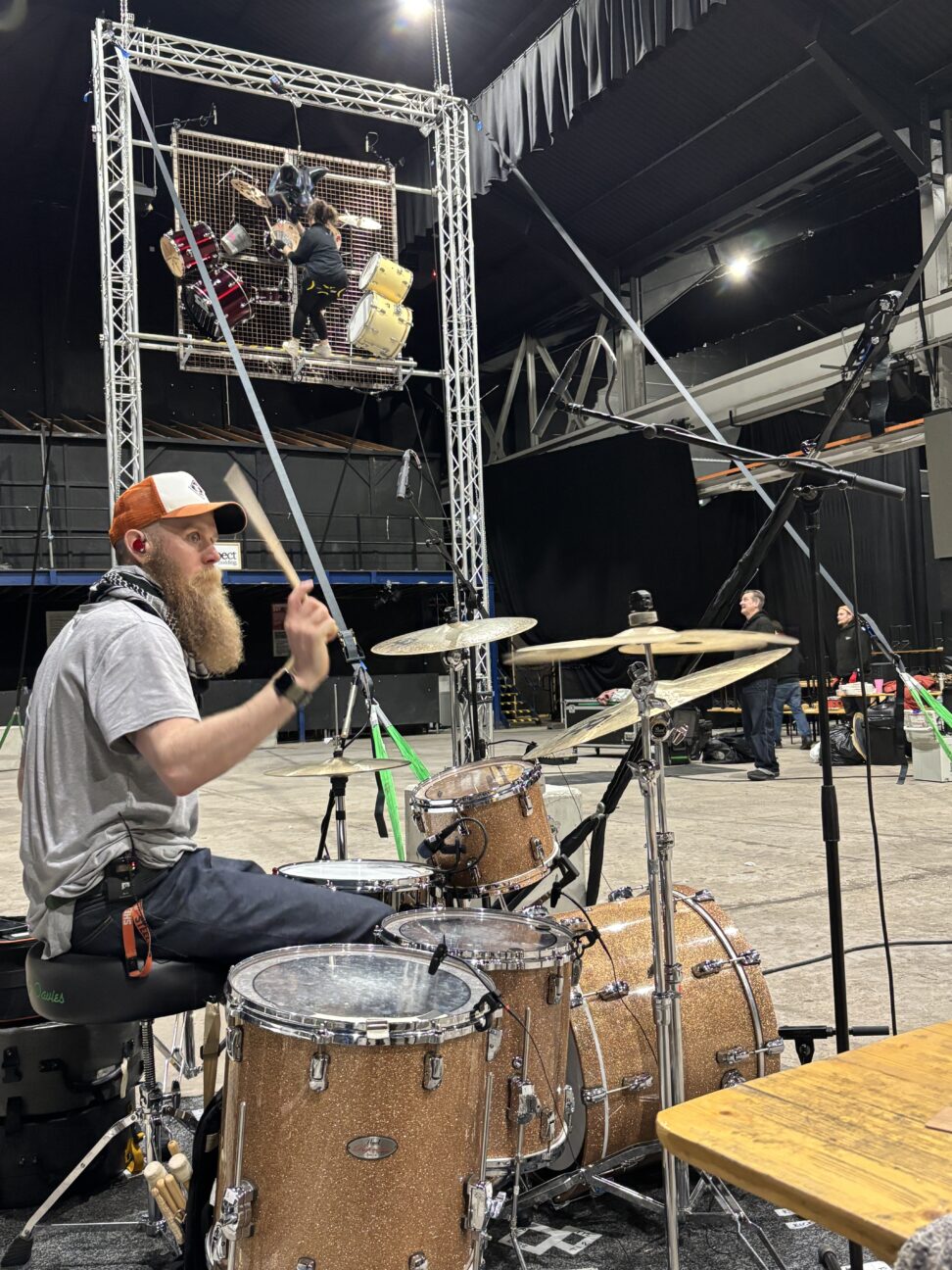 Photo of Craig Connet the drummer playing the drums with the aerial rig in the background