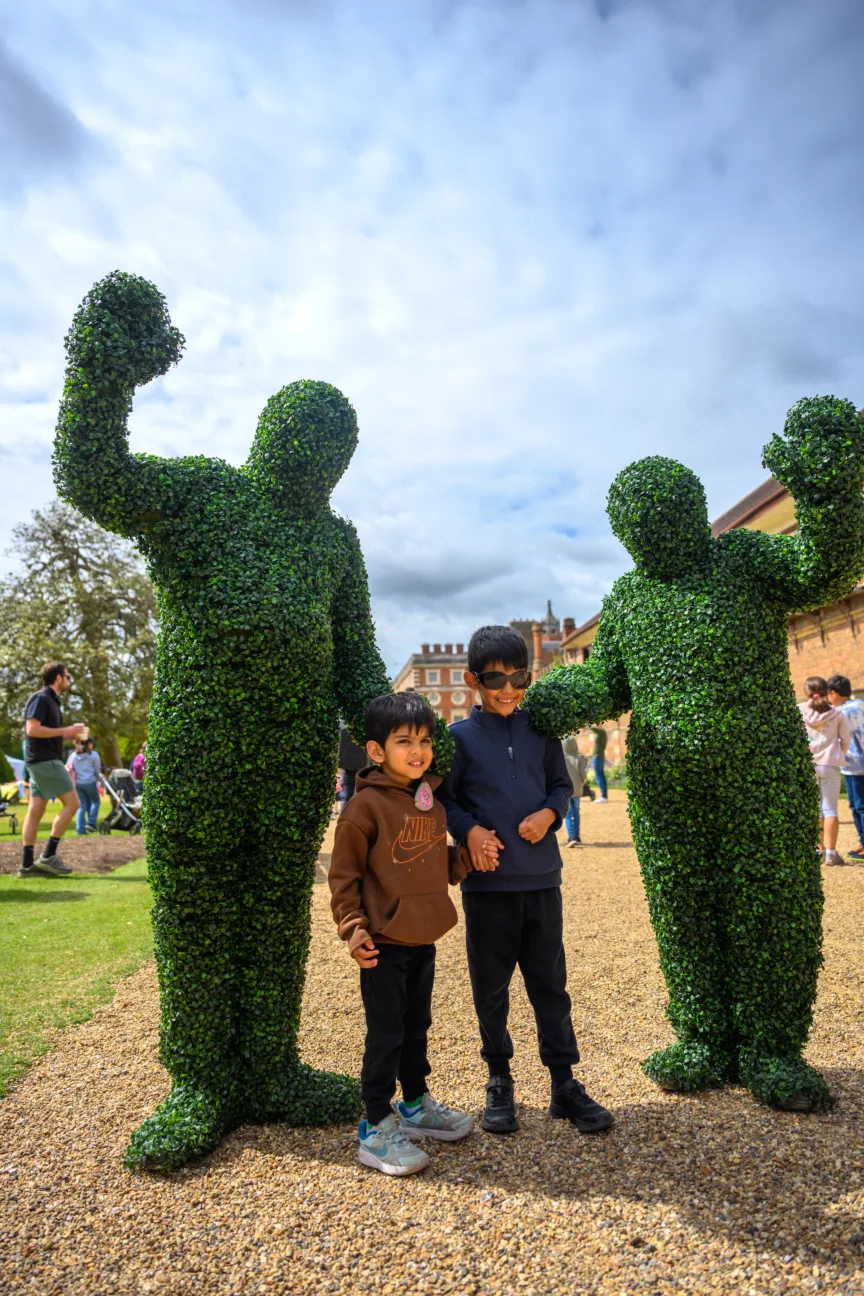 Two hedge people having a photo taken with two children