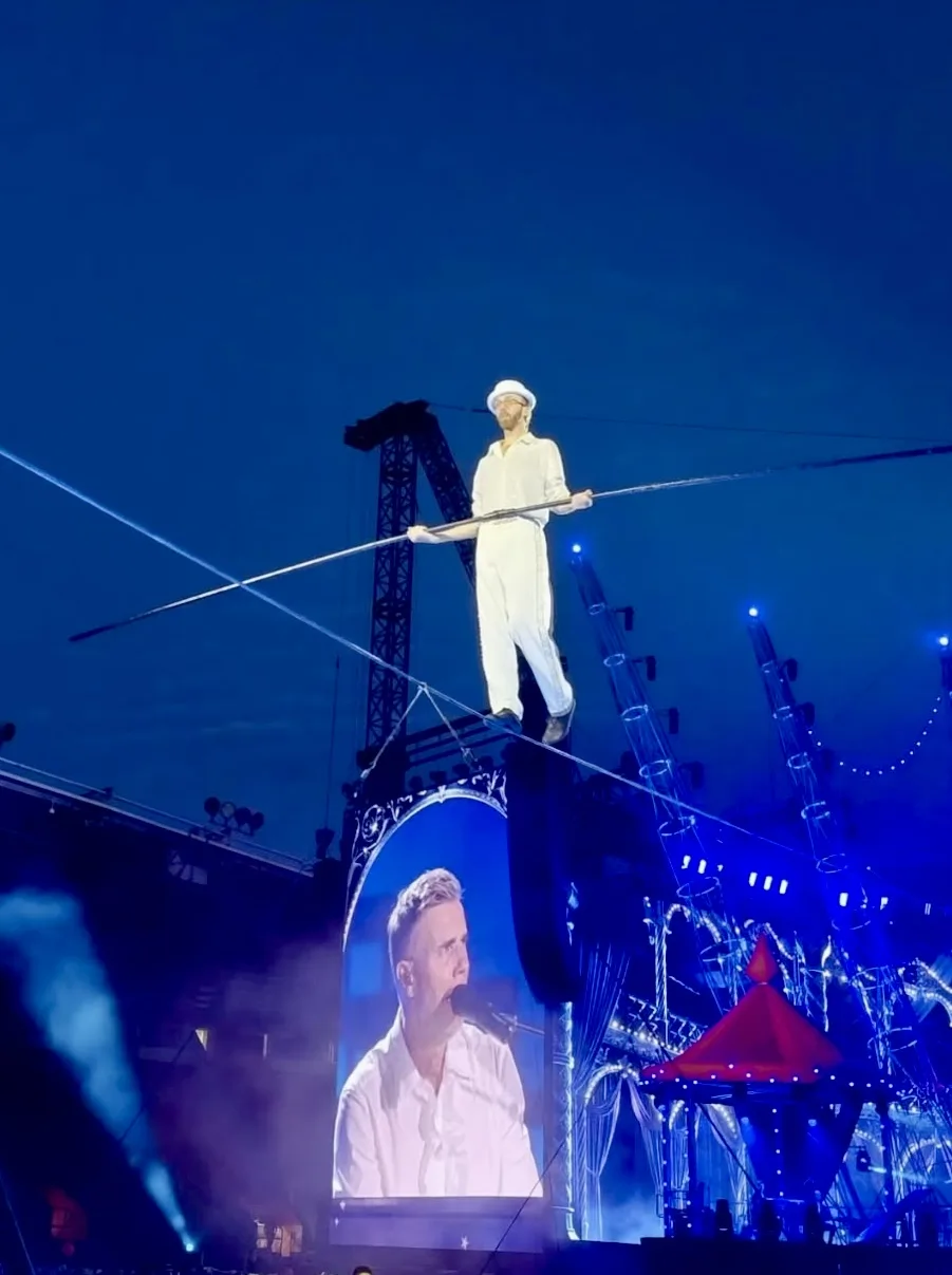 Photo of Ellis Grover on the highwire while Gary Barlow is singing