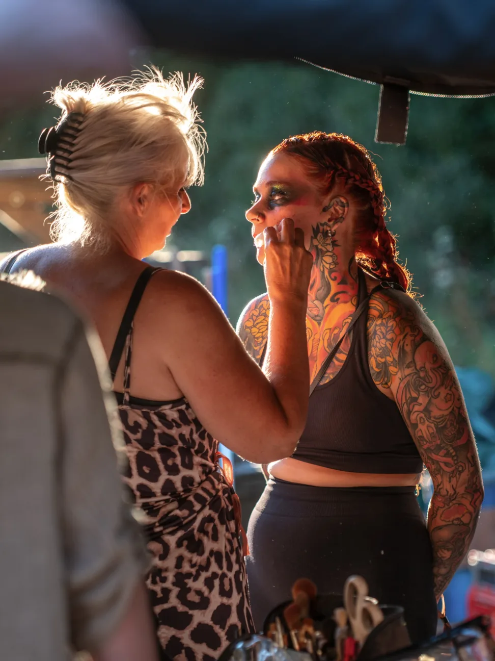 Behind the scenes shot of a makeup artist applying tribal dirt makeup to a performer.