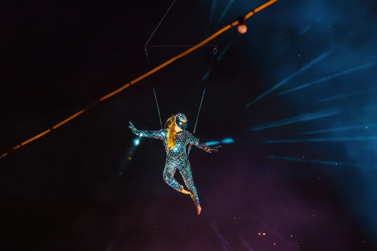 Aerialist wearing our Mirrorball costume flying high on a crane