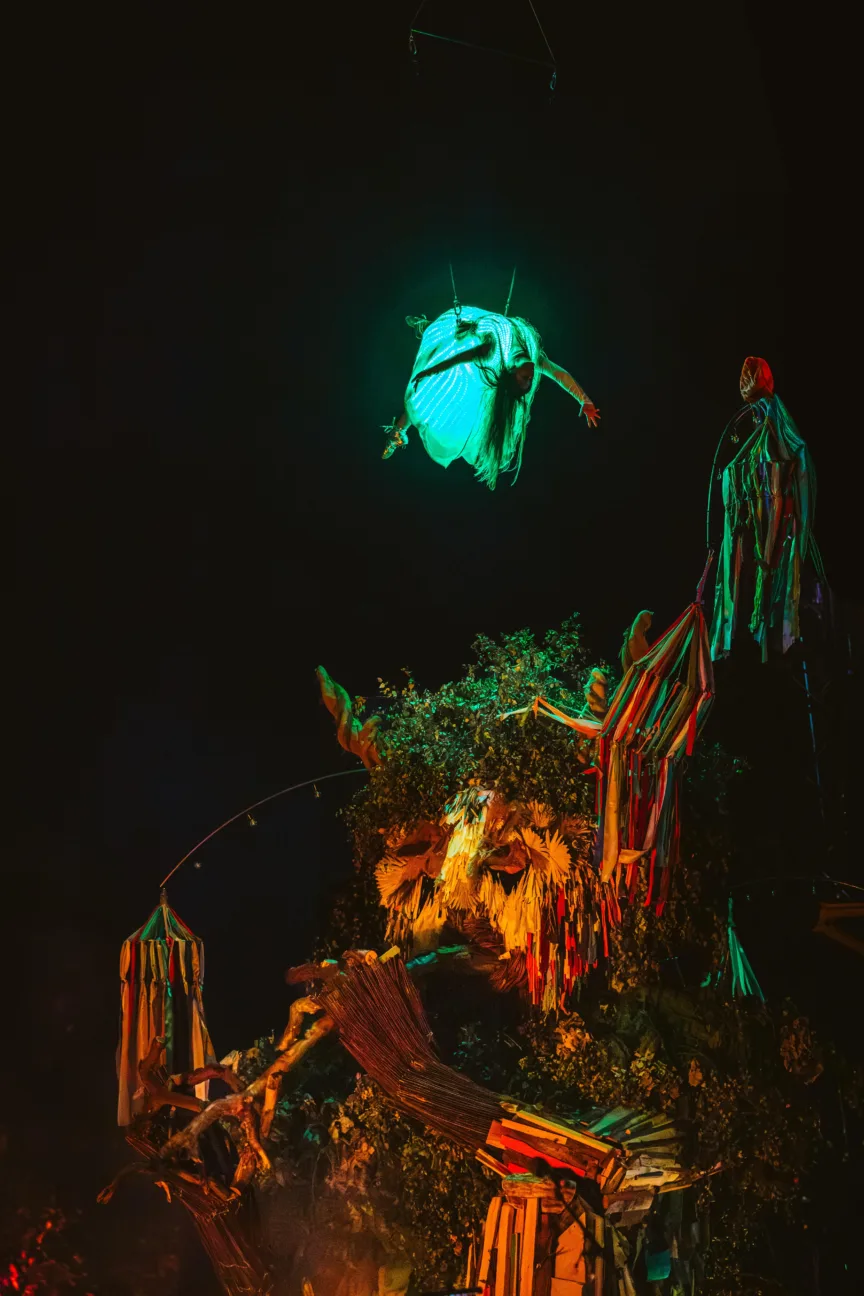 Aerialist wearing our LED dress flying over Green Man tree sculpture